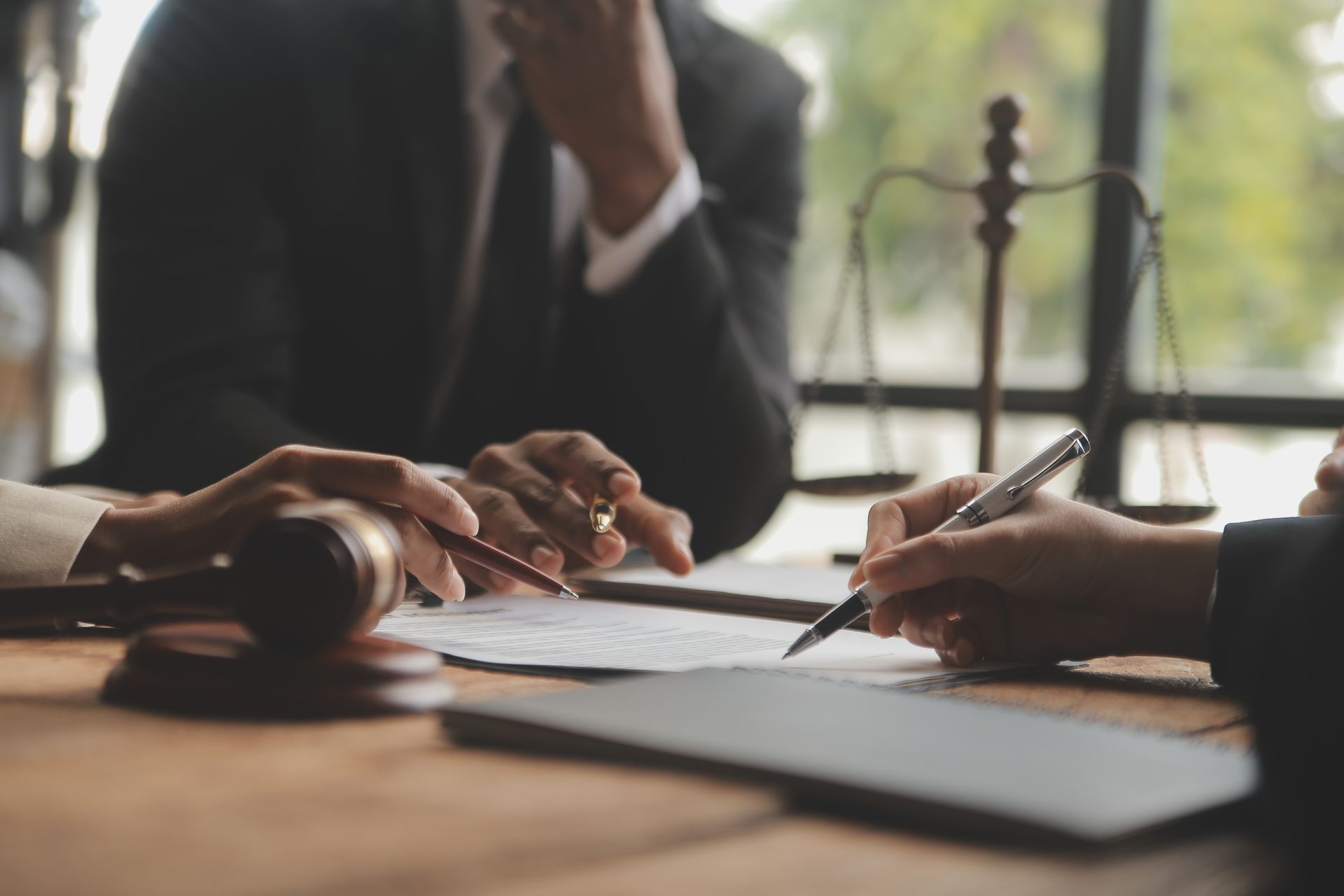 Legal professionals reviewing documents, scales of justice, and a gavel on a wooden desk.