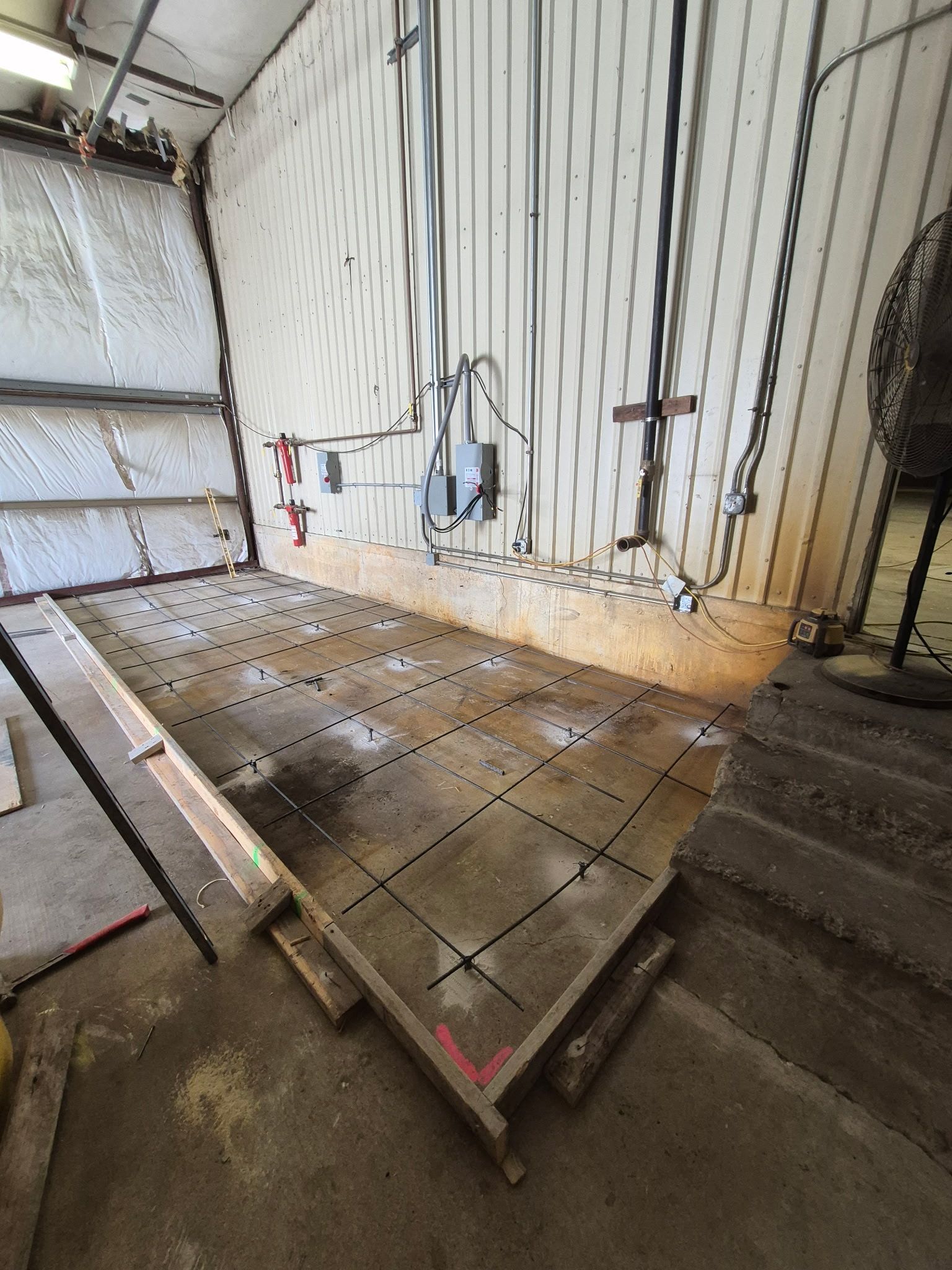 Empty industrial stairwell with metal wall panels, tiled floor, and exposed pipes on the right