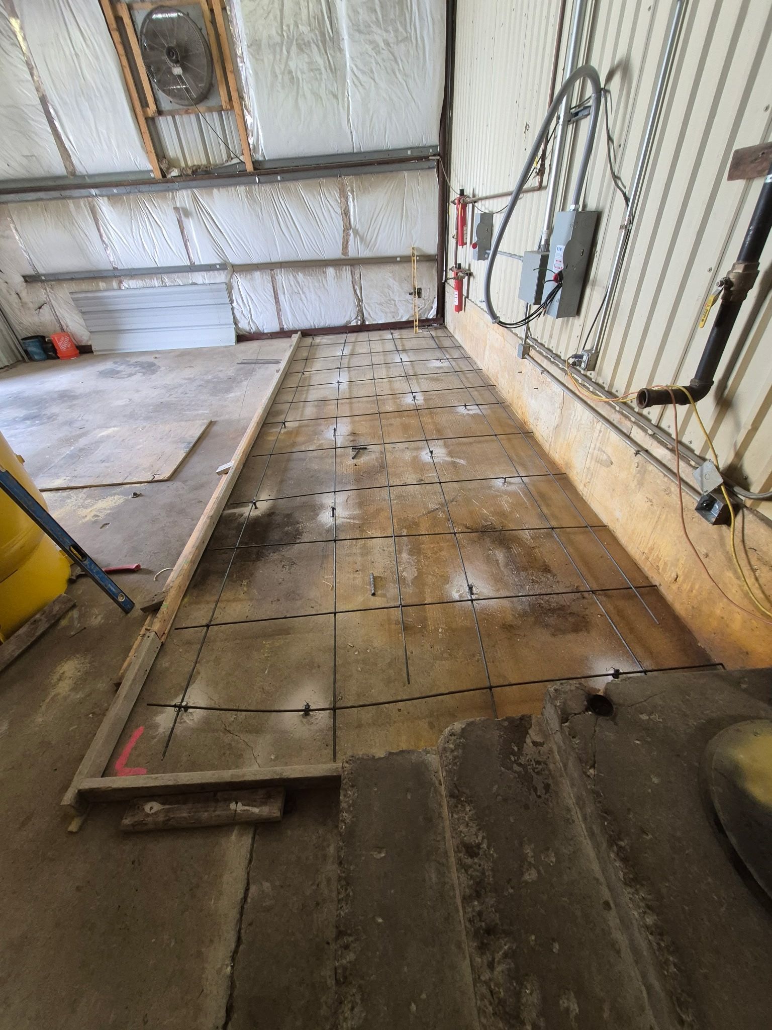 Industrial floor under renovation with exposed flooring panels and wall-mounted electrical boxes