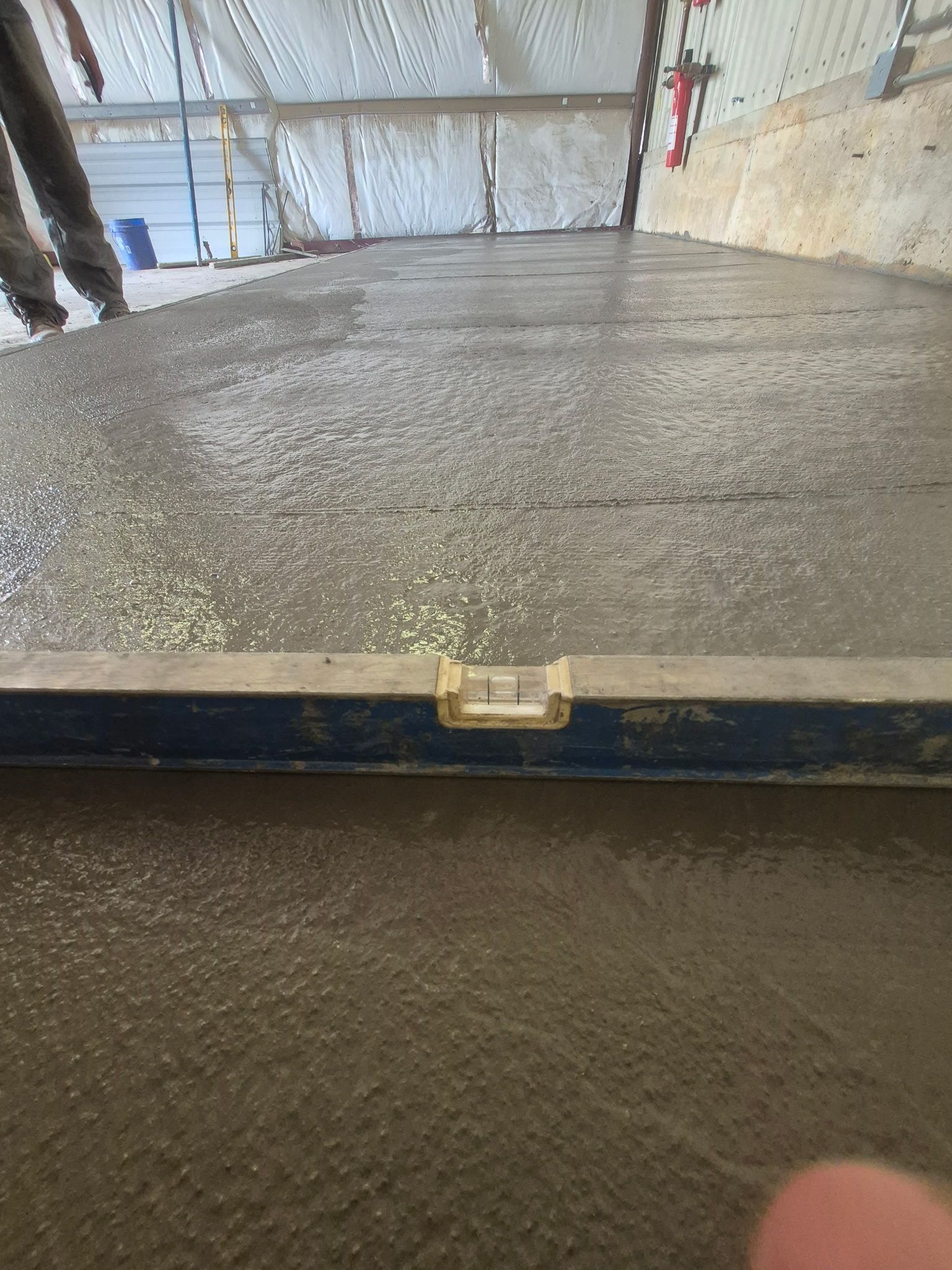 Freshly poured concrete being leveled in an indoor construction area