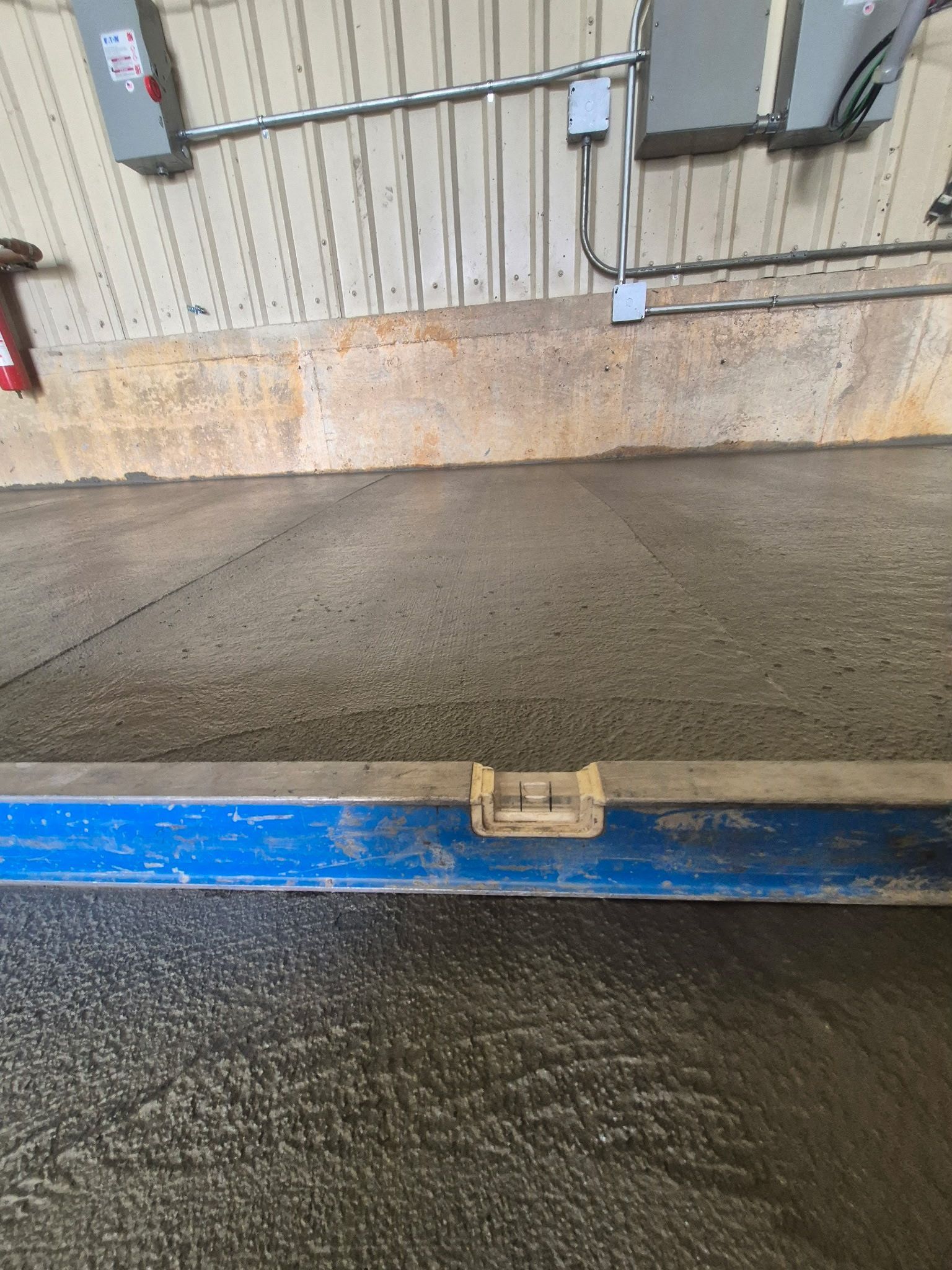 Blue metal threshold with a wet concrete floor and a ramp leading to a garage or loading area.
