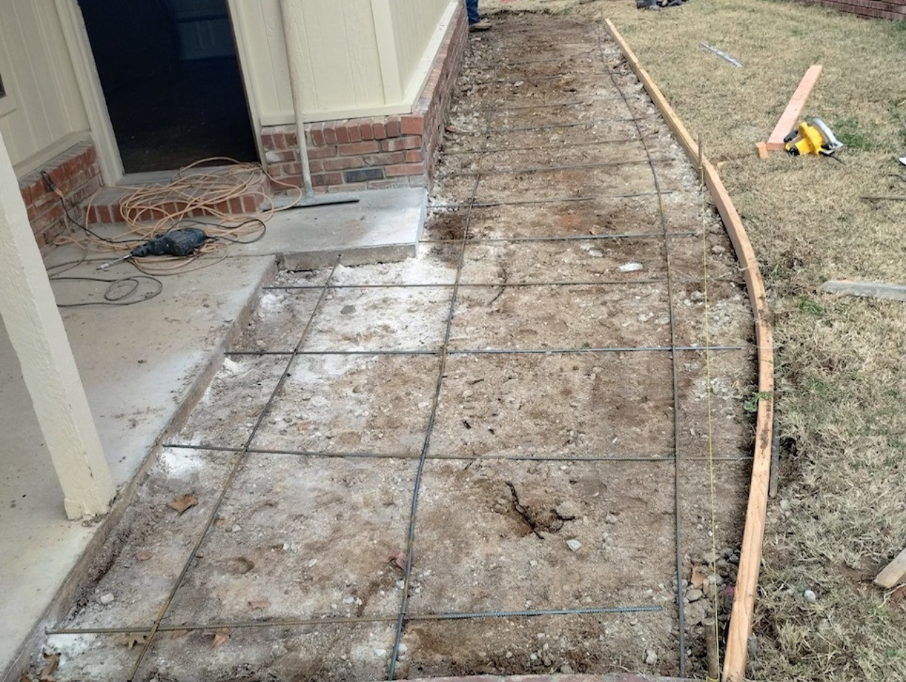 Concrete walkway under construction; rebar grid laid, wooden form edging a curved path.