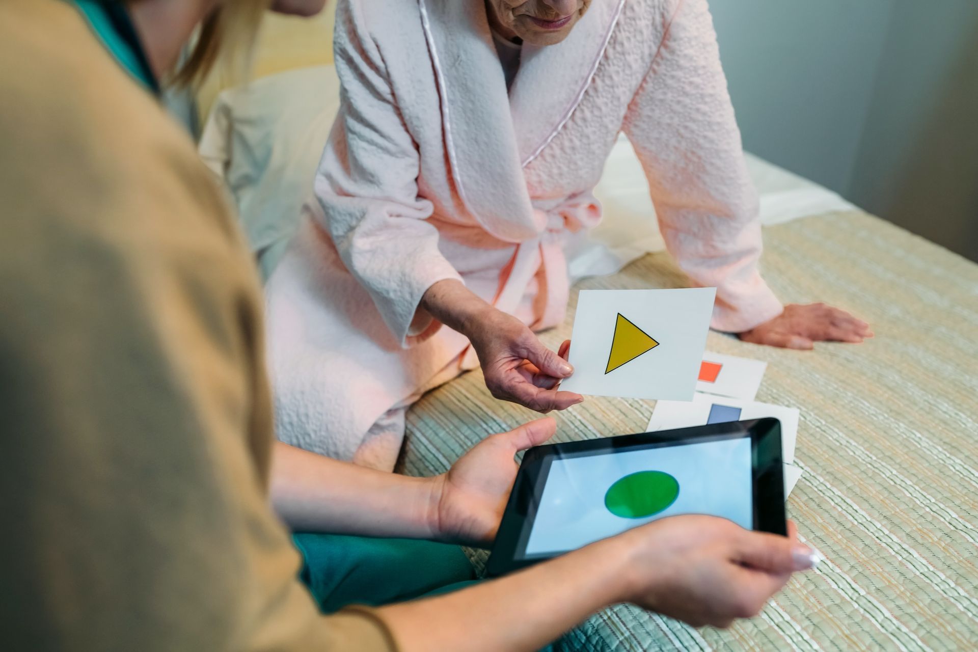 Eine Frau sitzt auf einem Bett und schaut auf ein Tablet.