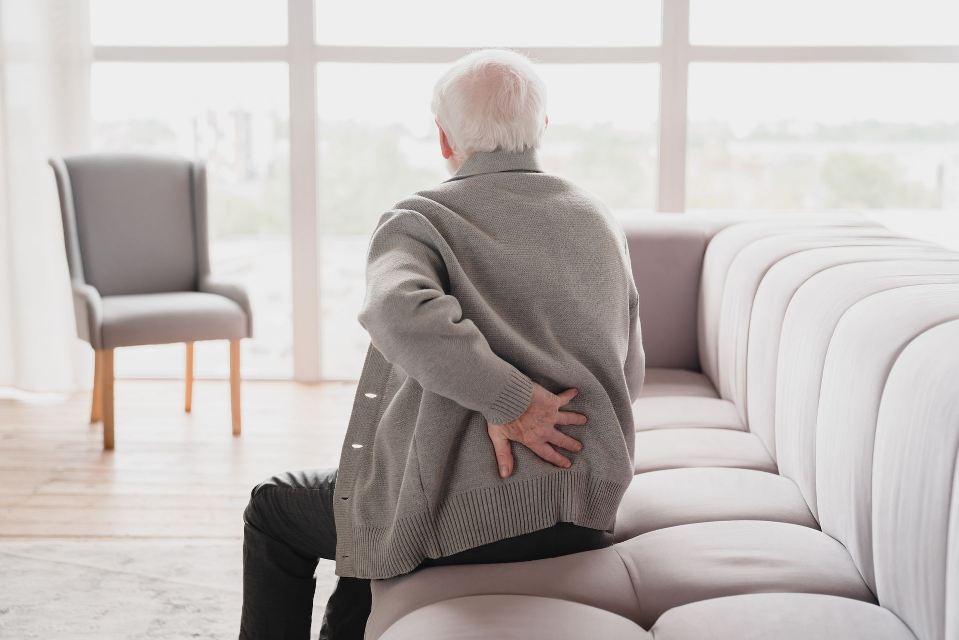 Eine Frau sitzt auf einem Sofa und hält ein kleines behindertes Mädchen im Arm. Körperliche Behinderung mit Ergotherapie behandeln