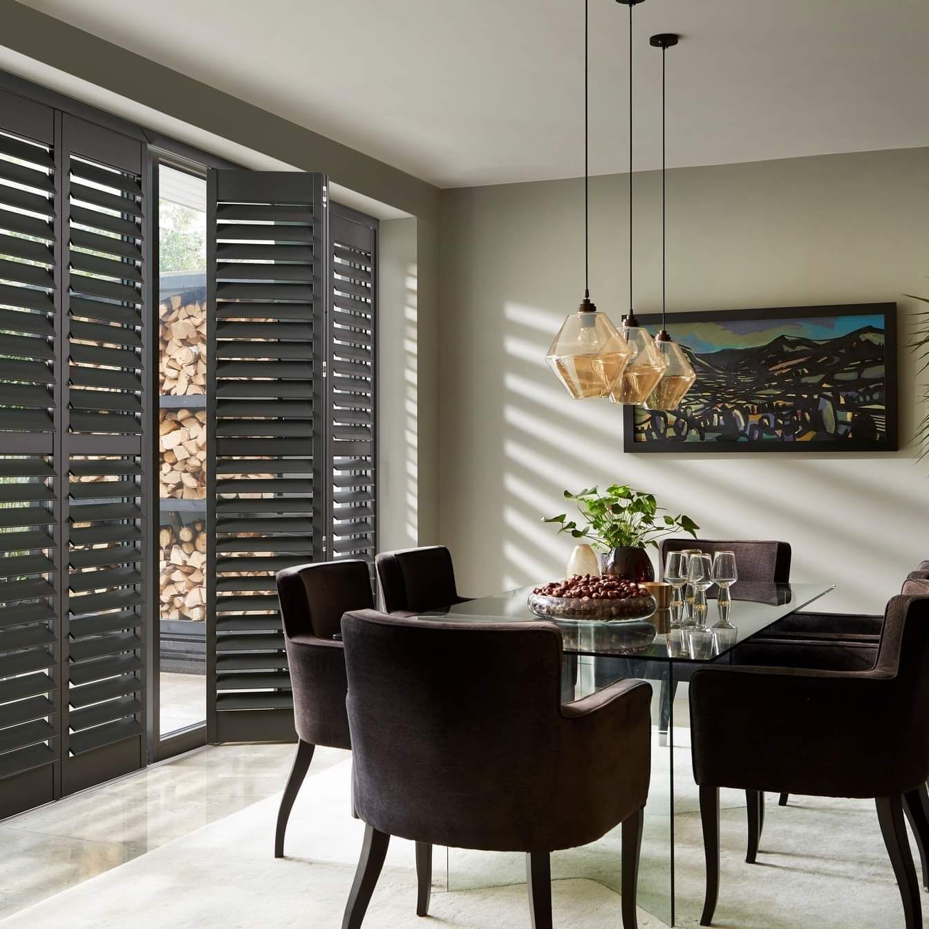 A dining room with a table and chairs and shutters on the windows