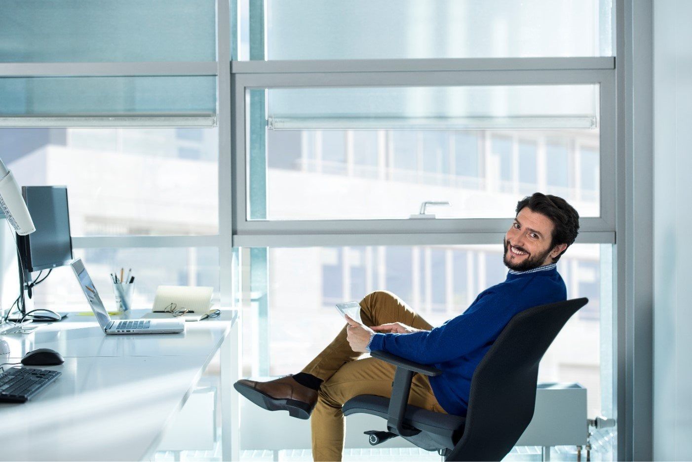 A man is sitting in an office chair with his legs crossed.
