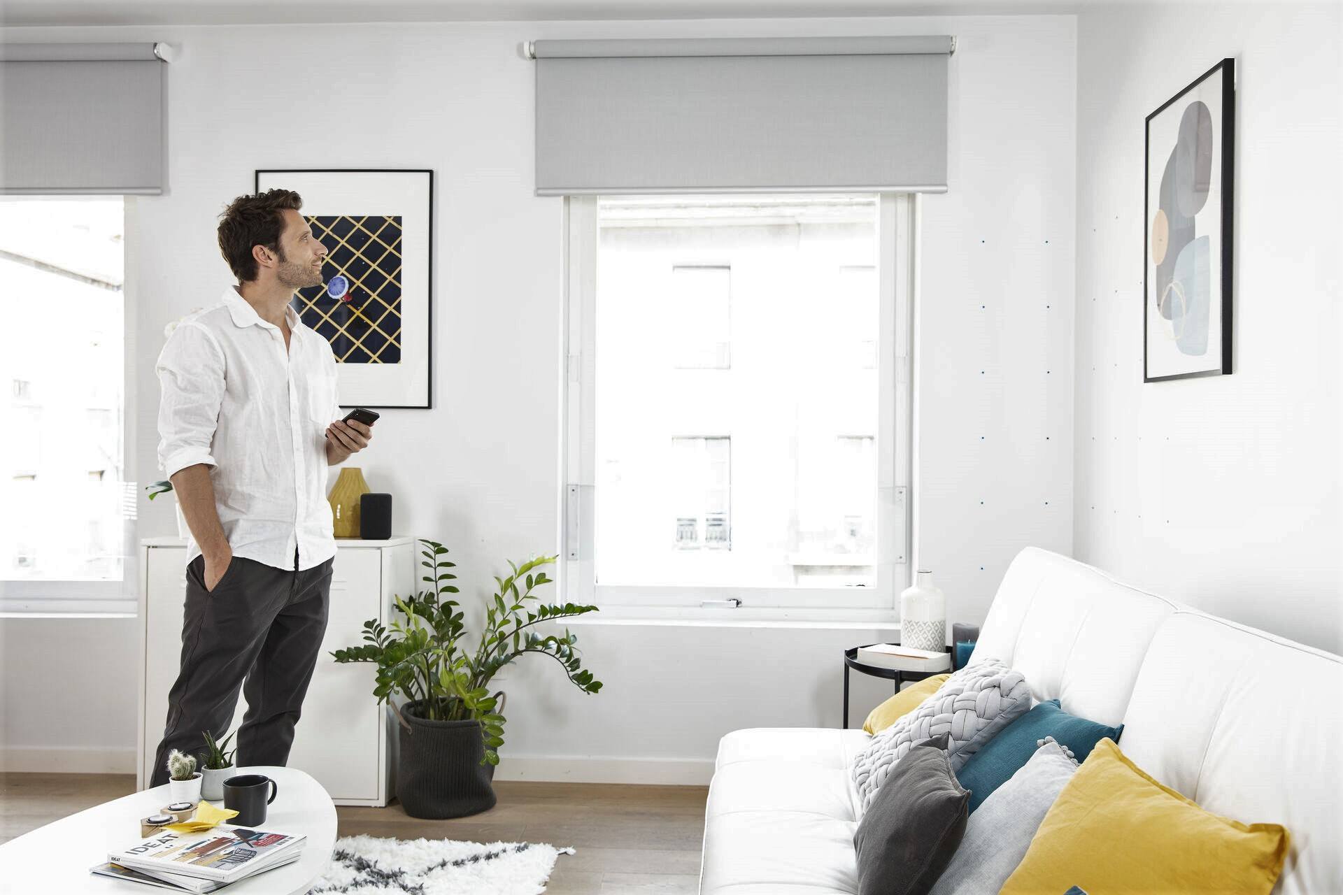 A man is standing in a living room holding a remote control.