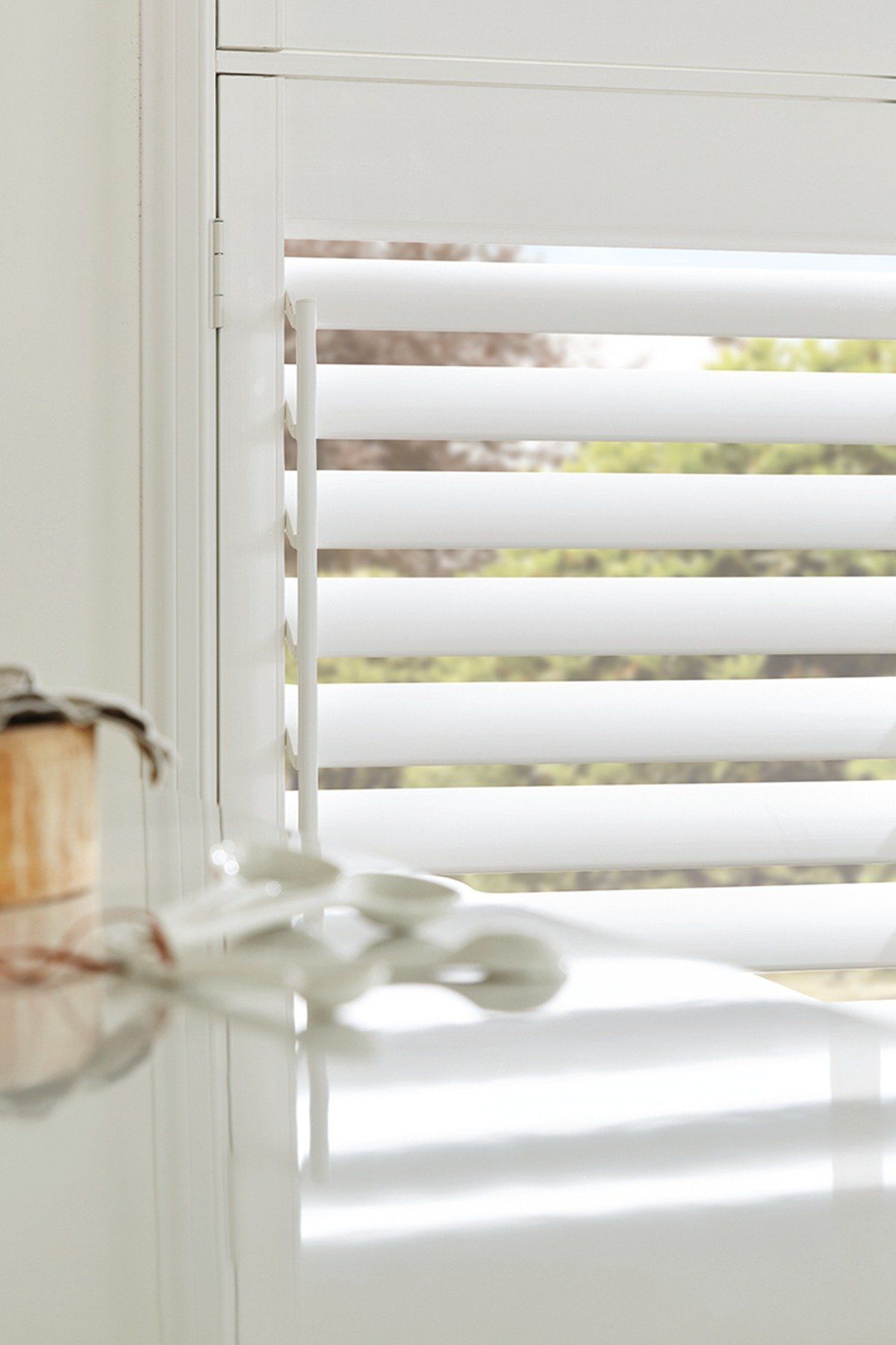 A close up of a white shutter on a window.