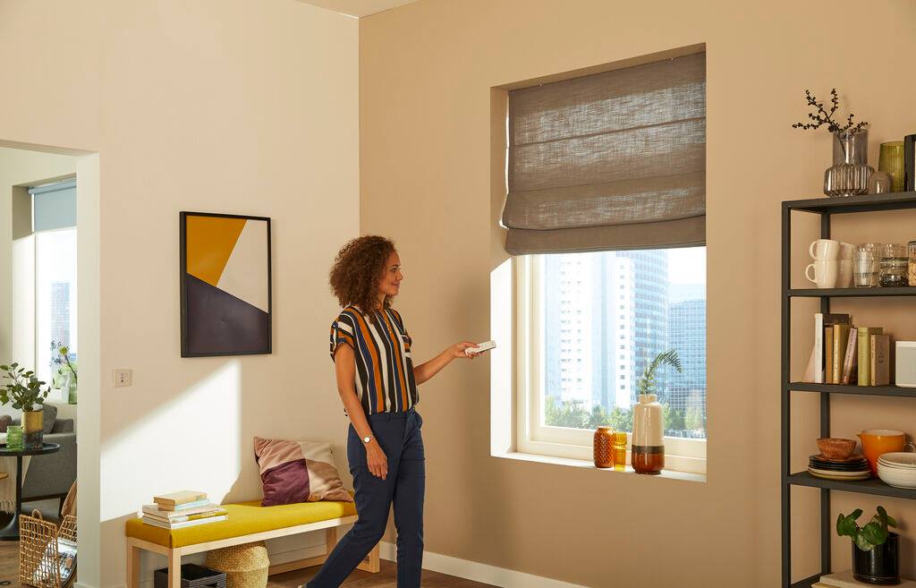 A woman is standing in front of a window in a living room.