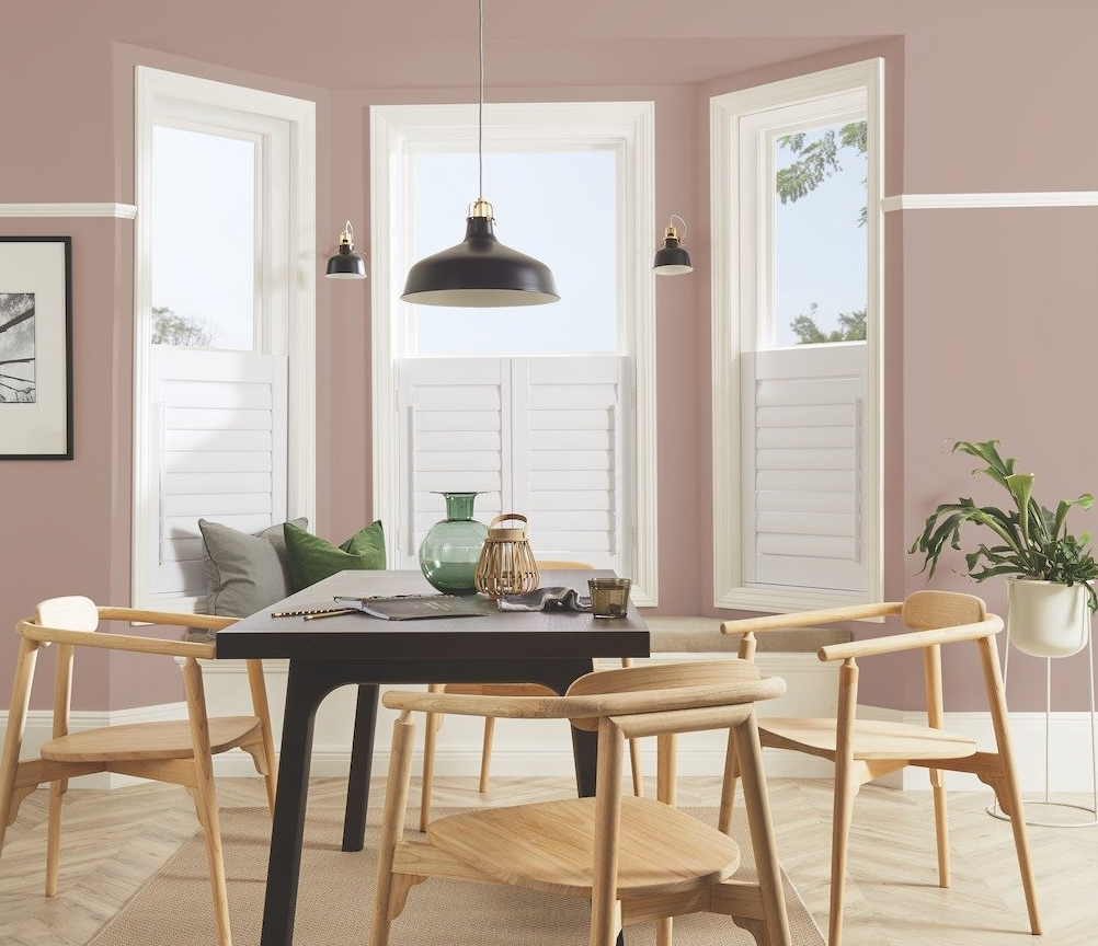 A dining room with a table and chairs and pink walls