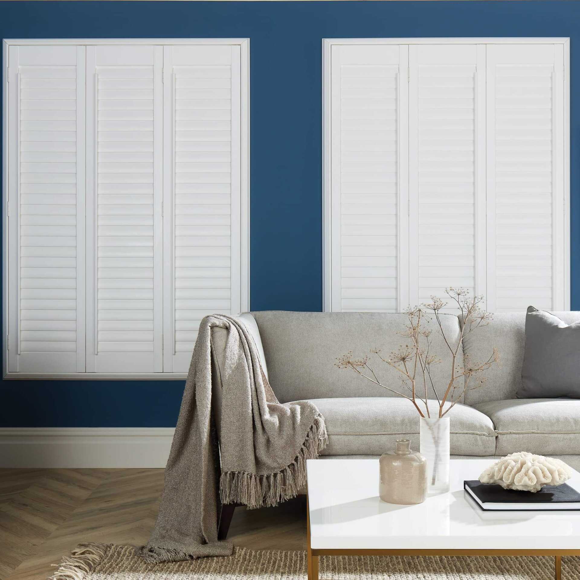 A living room with a couch and shutters on the windows