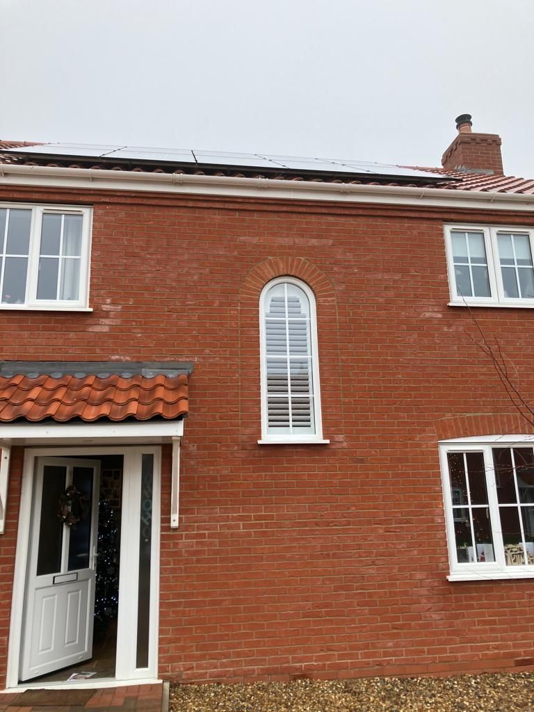 A red brick house with white windows and a chimney on the roof.