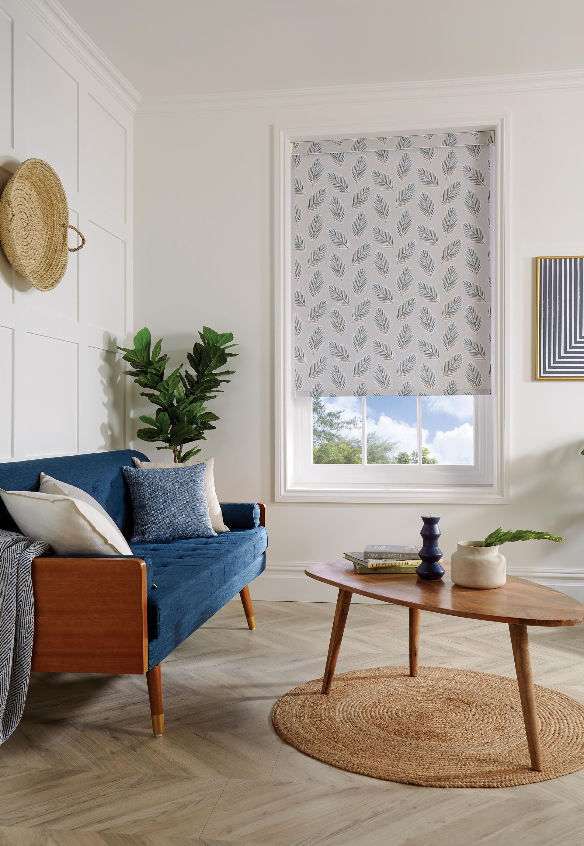 A living room with a blue couch , a coffee table , and a window.