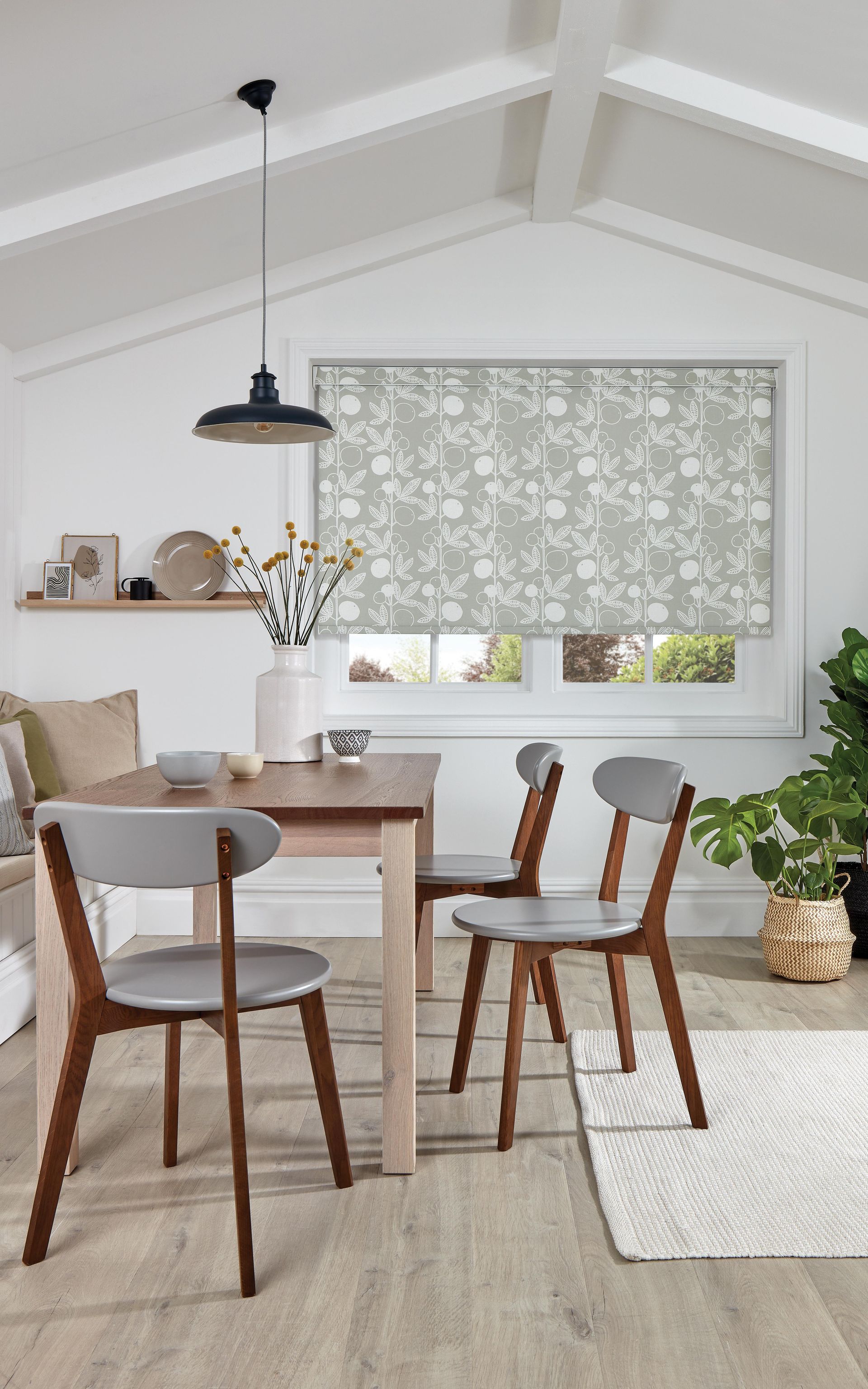A dining room with a table and chairs and a window with a blind on it.