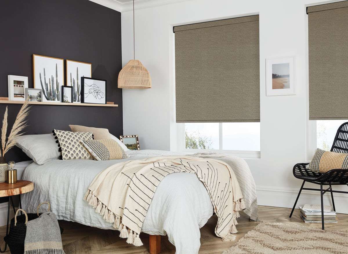 A bedroom with a bed , chair , table and two windows.