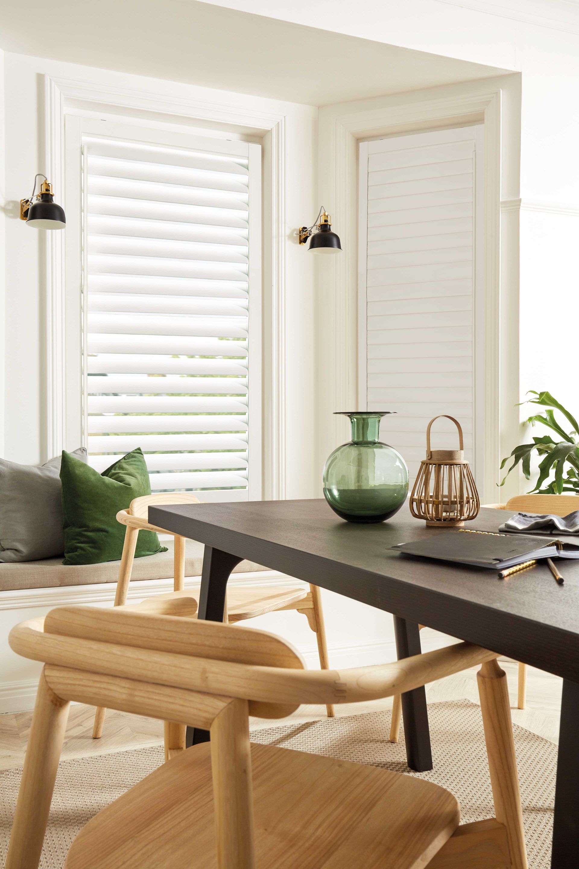 A dining room with a table and chairs and a vase on the table.