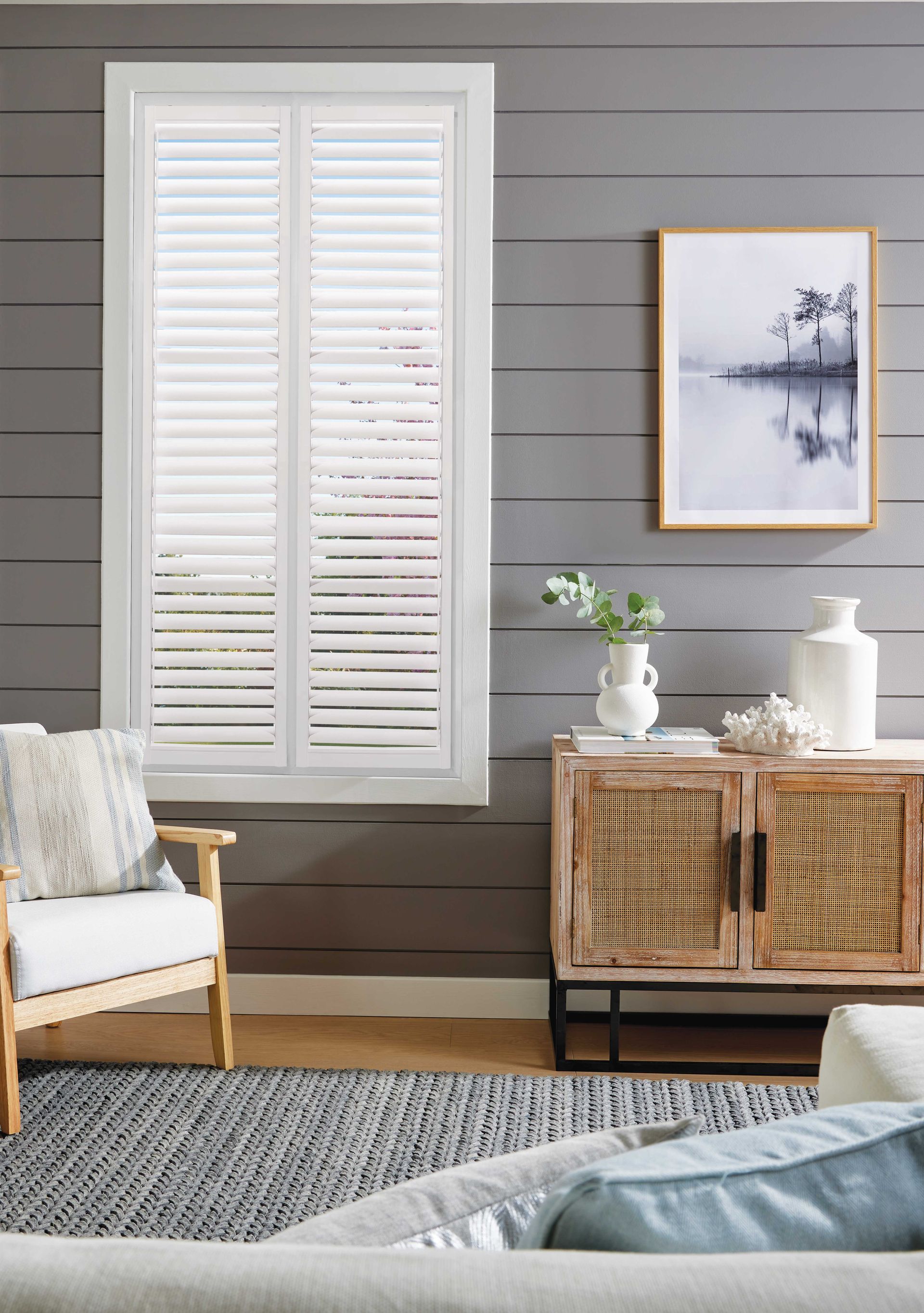 A living room with a couch , chair , table and shutters on the window.