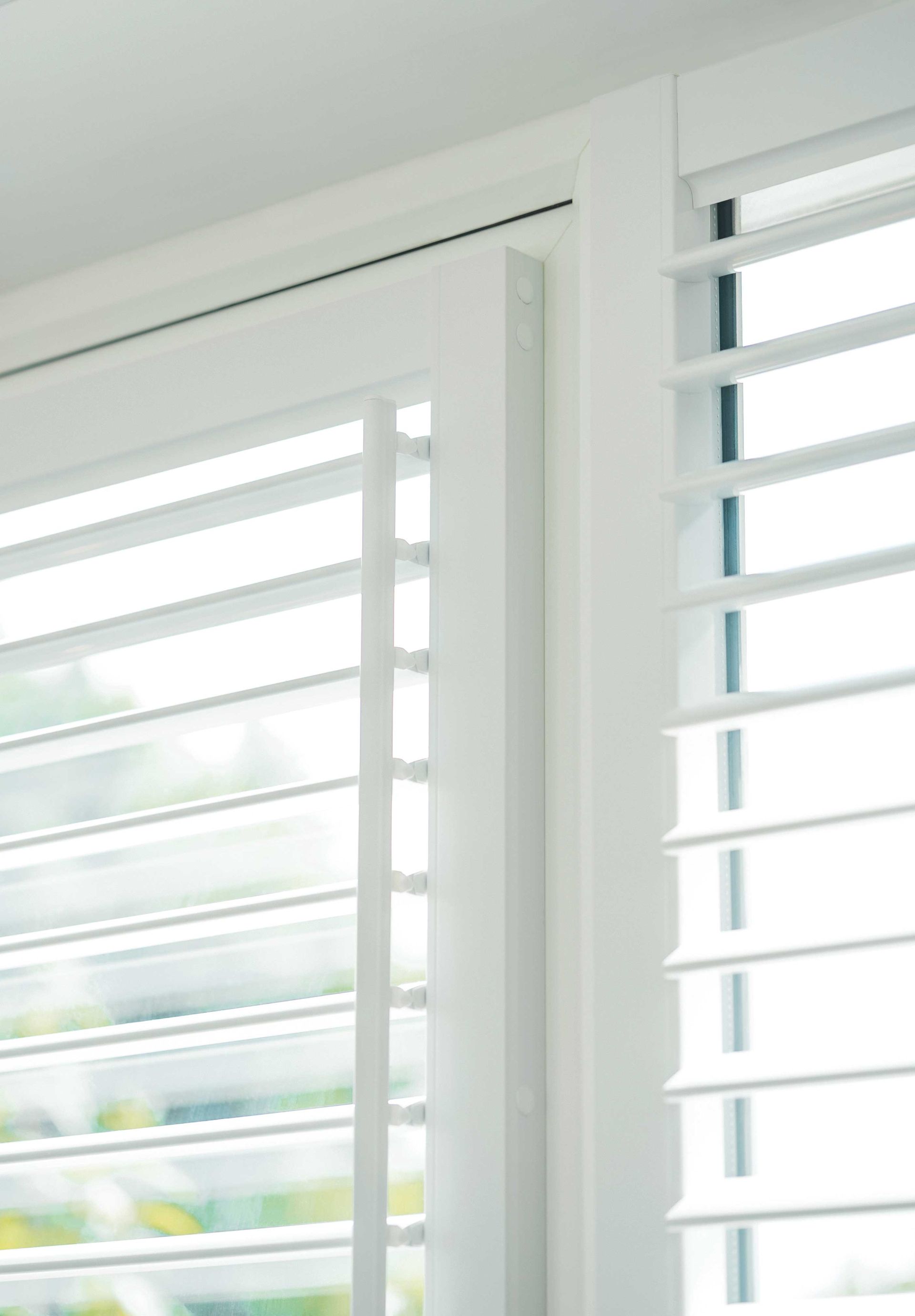A close up of a window with white shutters on it