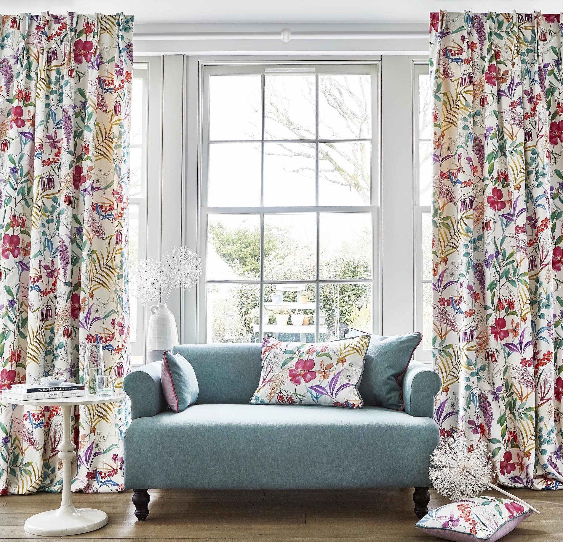 A living room with a blue couch and floral curtains