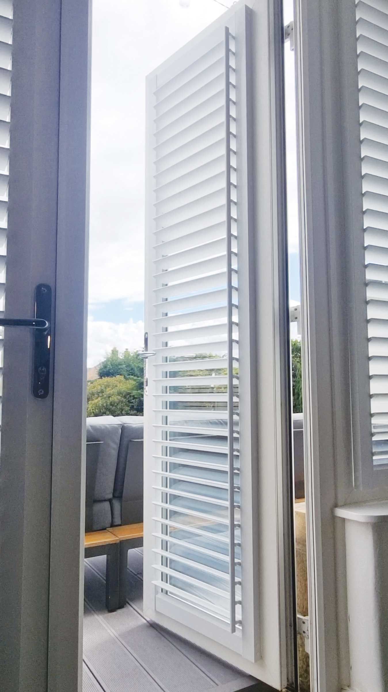 A door with white shutters on it is open to a balcony.