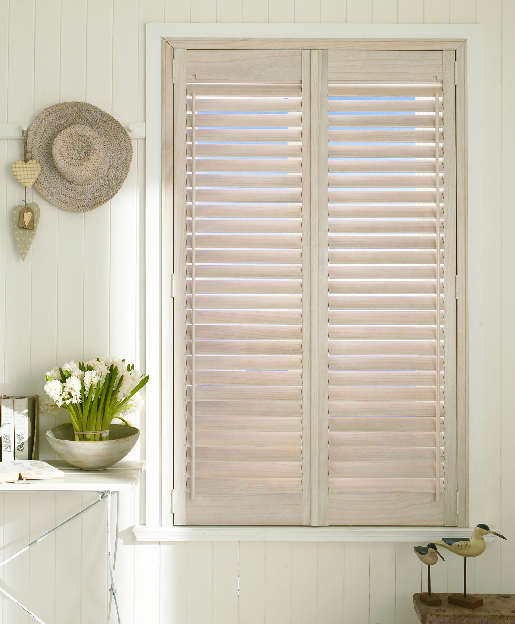 A window with shutters and a vase of flowers