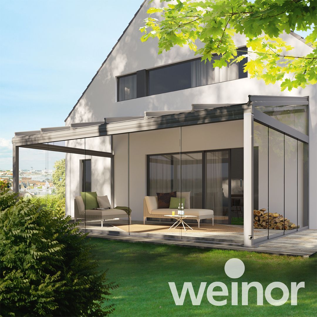 A white house with a patio and a weinor logo