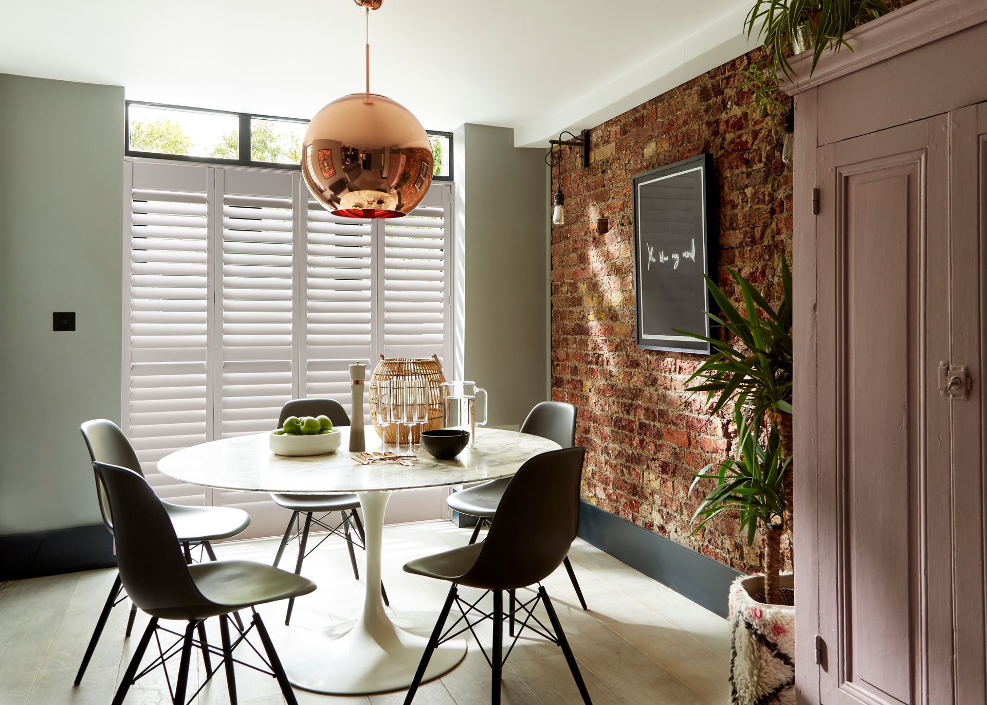 A dining room with a table and chairs and a brick wall.