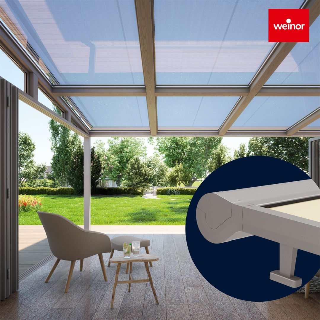 A patio with a table and chairs under a glass roof.