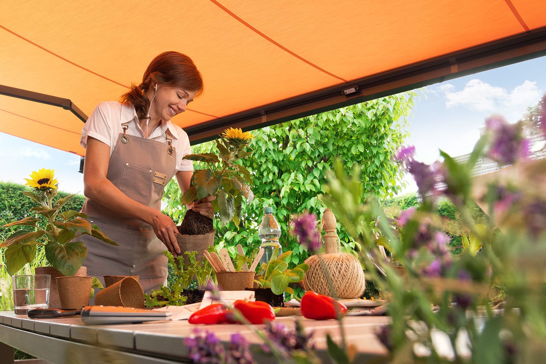 A woman is standing at a table under an awning.