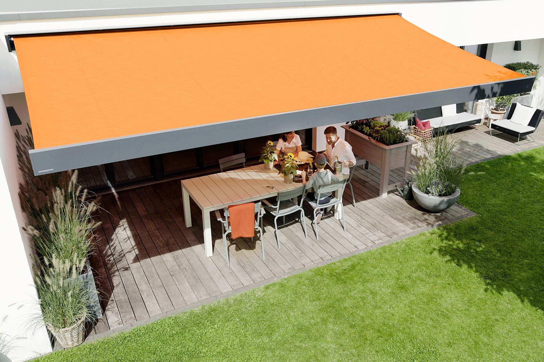 A man and woman are sitting under an orange awning on a patio.