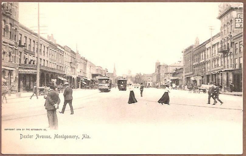 A black and white photo of a city street with people walking down it.