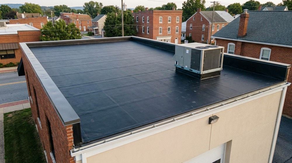 Flat black rooftop with HVAC unit on a brick building in an urban area