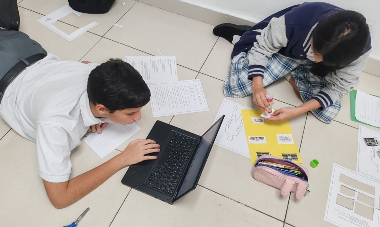 Trabajo colaborativo entre estudiantes con laptops y material educativo en CEI Montessori.