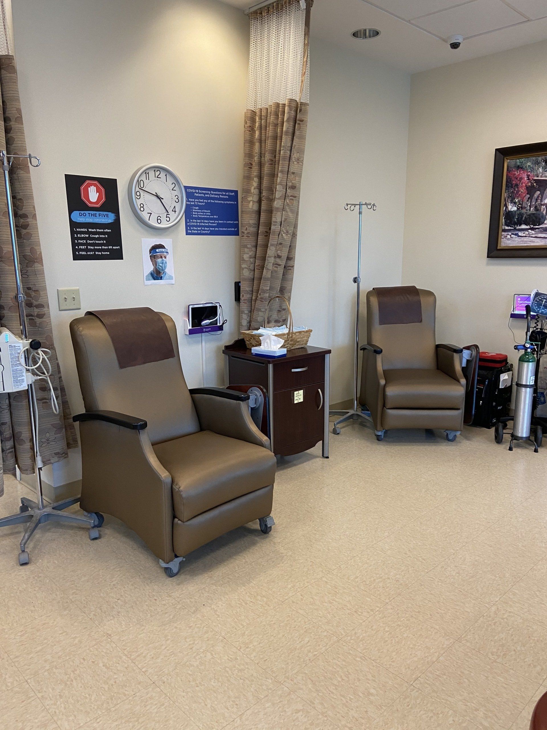 Two brown chairs in a medical setting with infusion poles, curtains, and supplies.