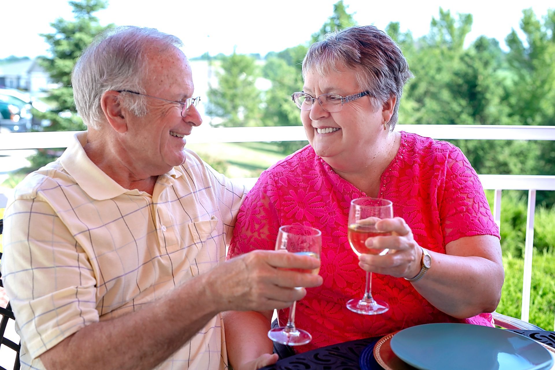 retired couple cheering wine glasses outdoors at retirement community Retirement Community dining experience