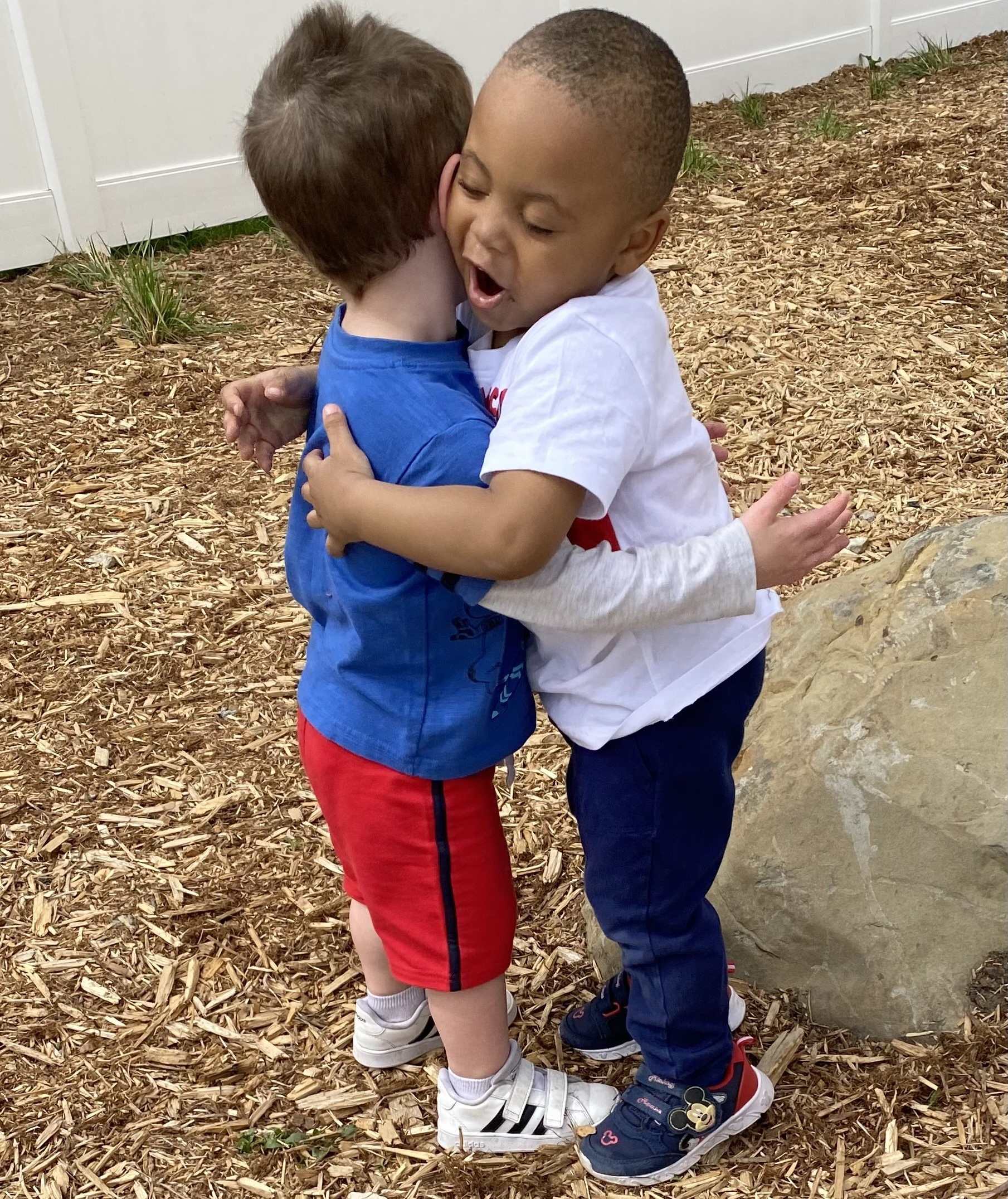 two little kids hugging each other on the playground outside of It Takes a Village Childcare Center