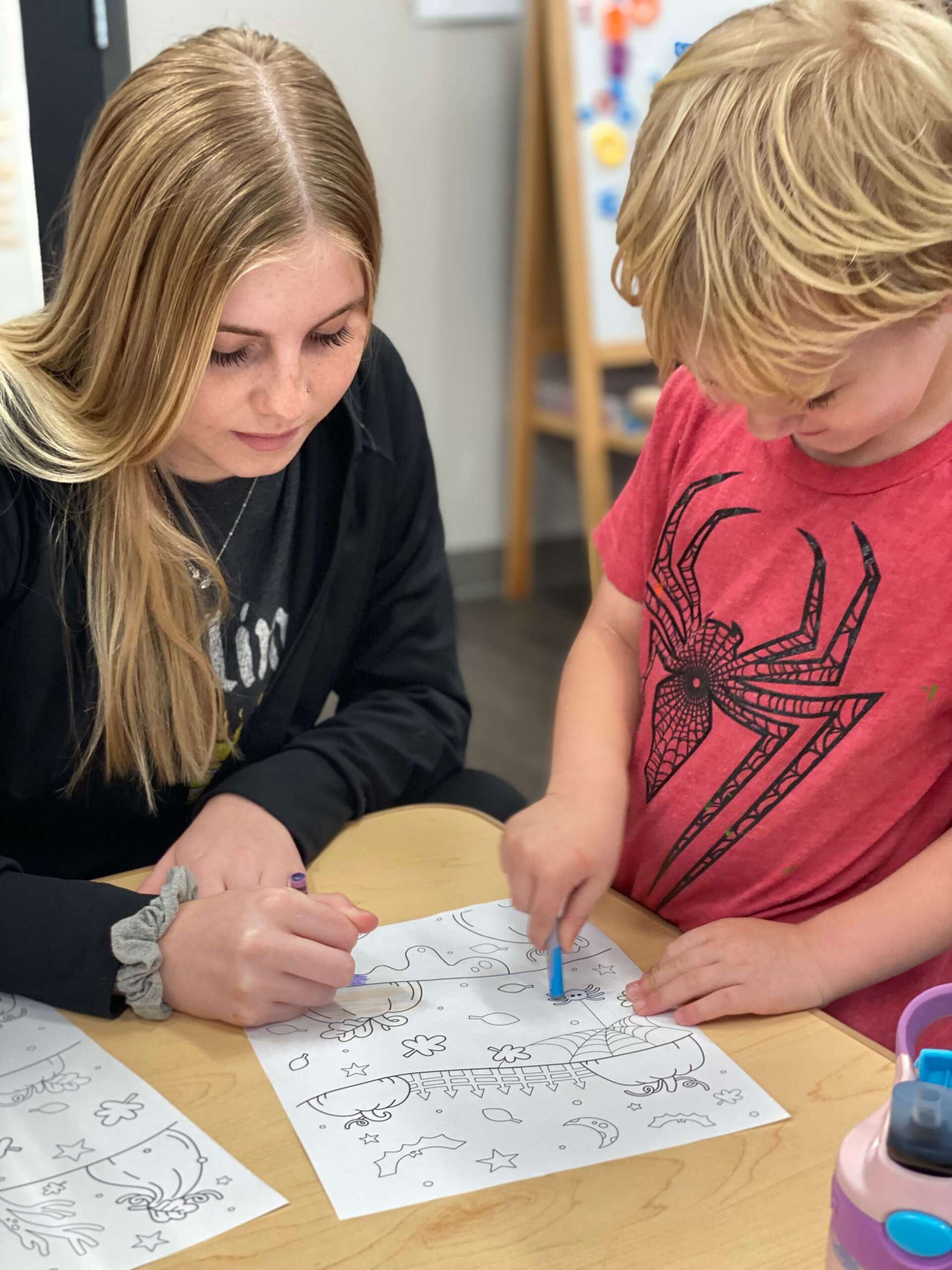 It Takes a Village Childcare employee teaching a child how to color