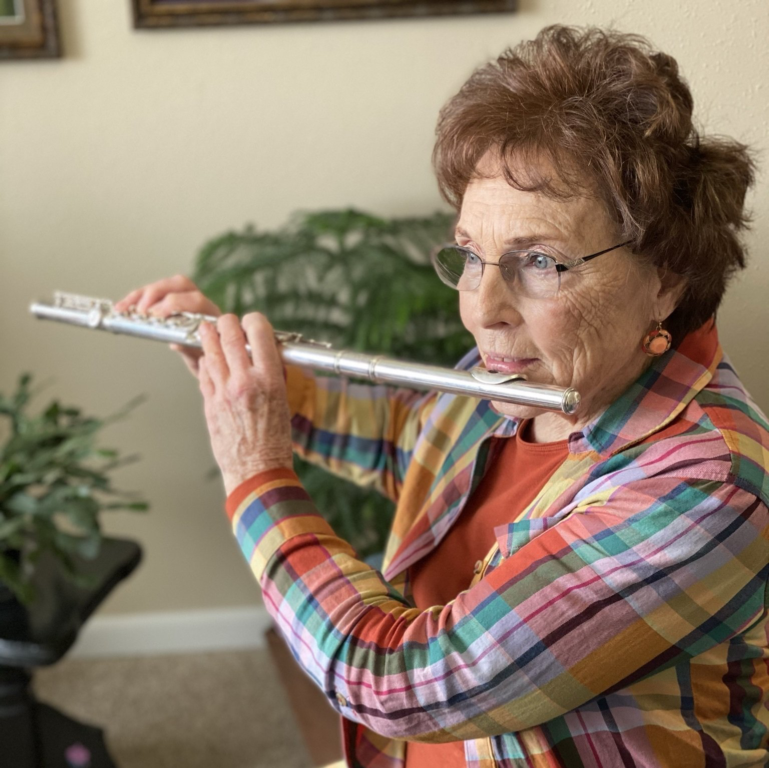 Retired lady playing music on her flute in her independent apartment