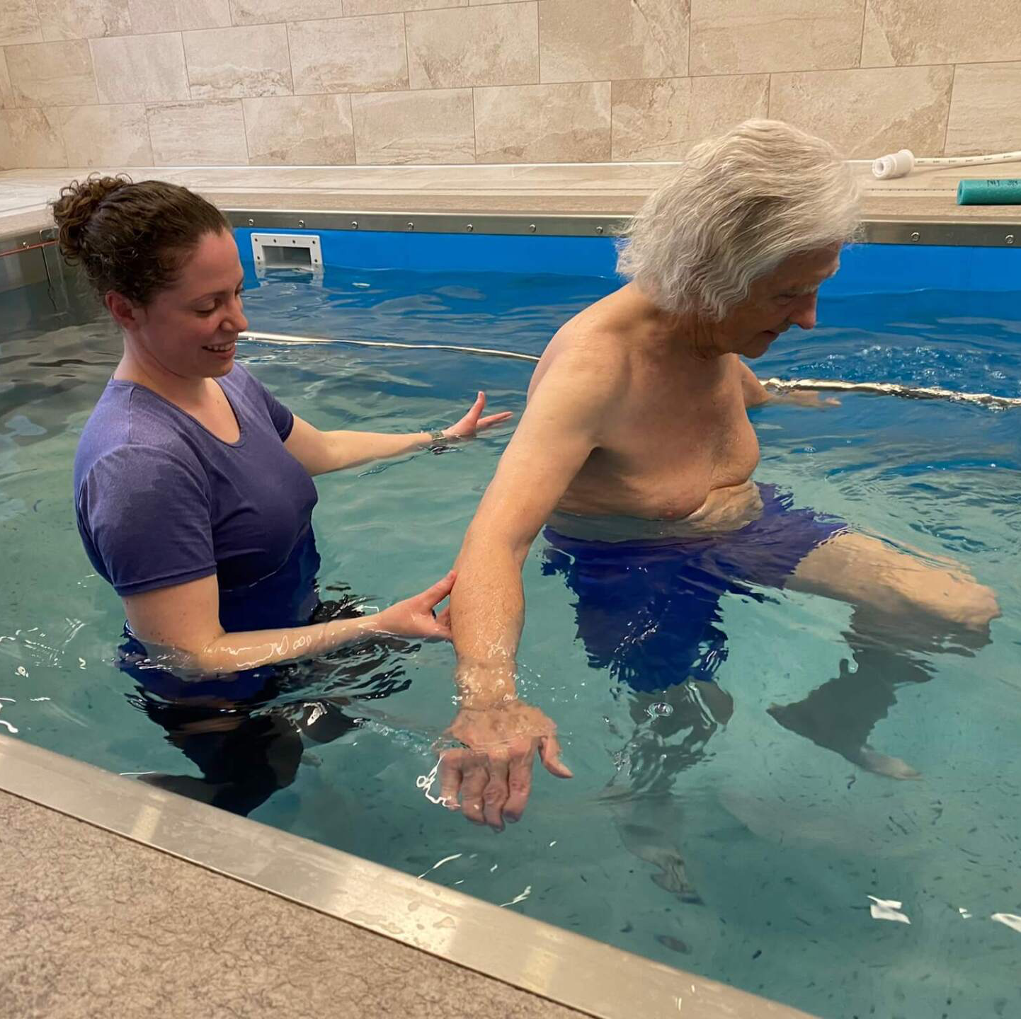 resident walking in hydro pool with physical therapist