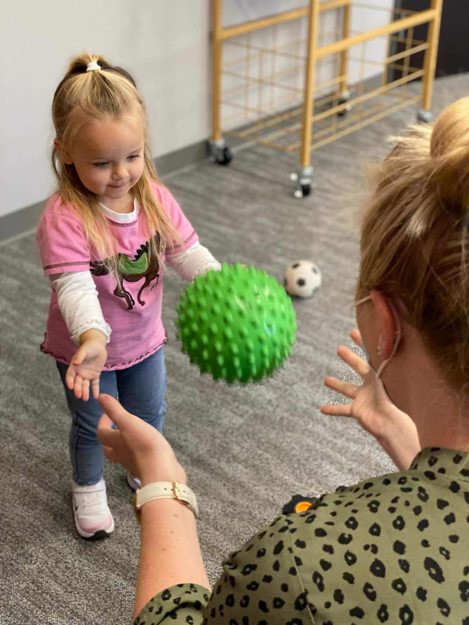child playing catch with an Occupational Therapist in the playroom of It Takes a Village Childcare