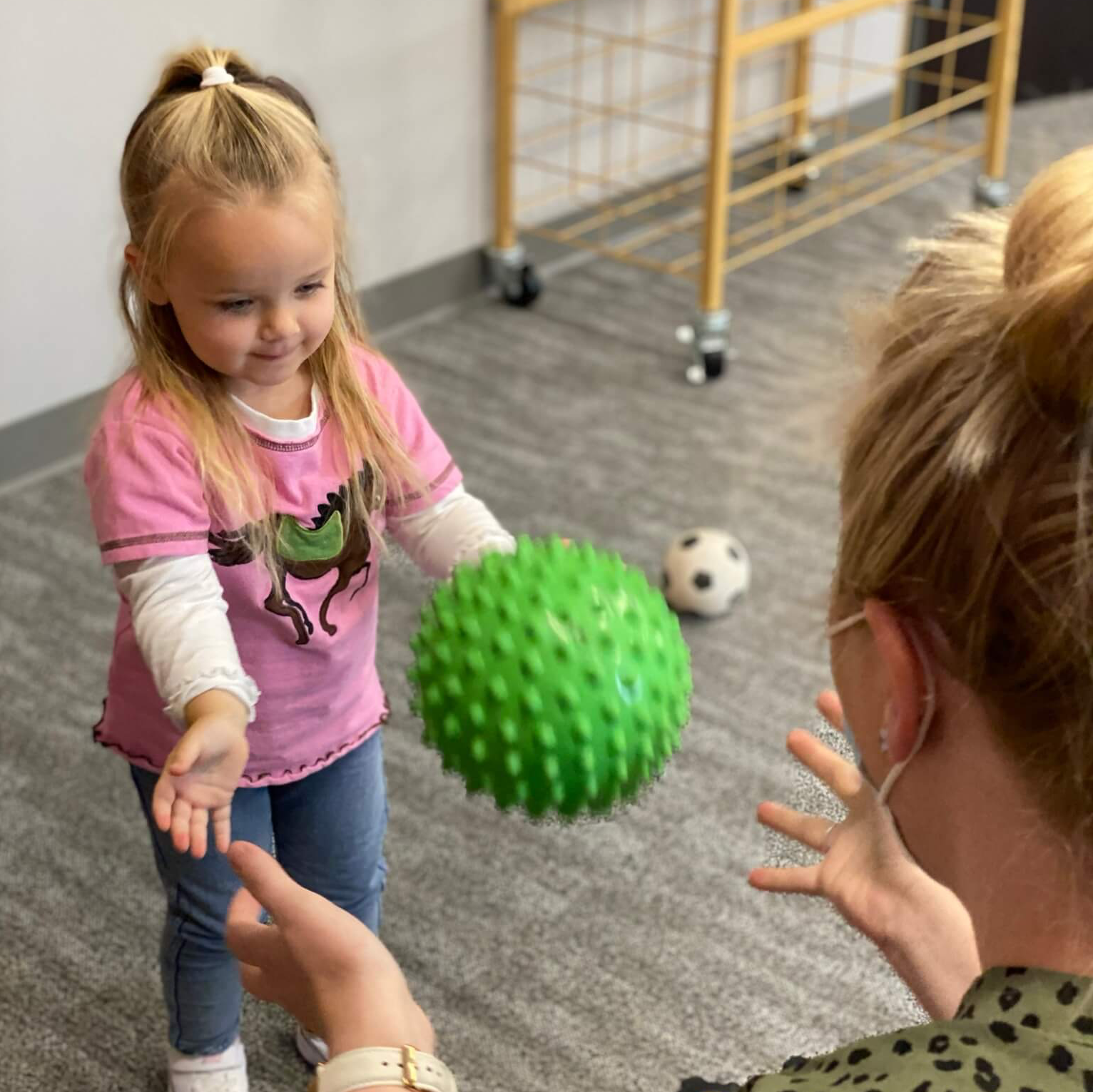 child playing catch with an Occupational Therapist in the playroom of It Takes a Village Childcare