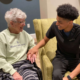 caregiver holding hands with a resident in Wellspring Living Health Center