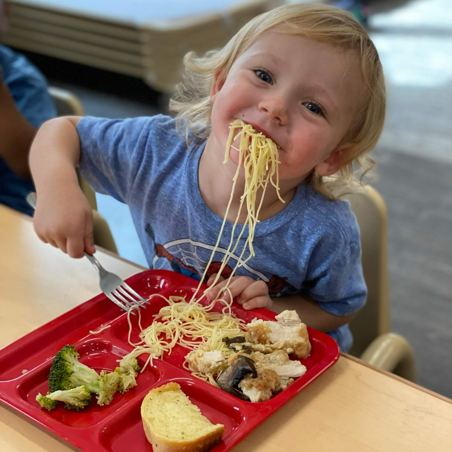 child eating with spaghetti hanging out of his mouth