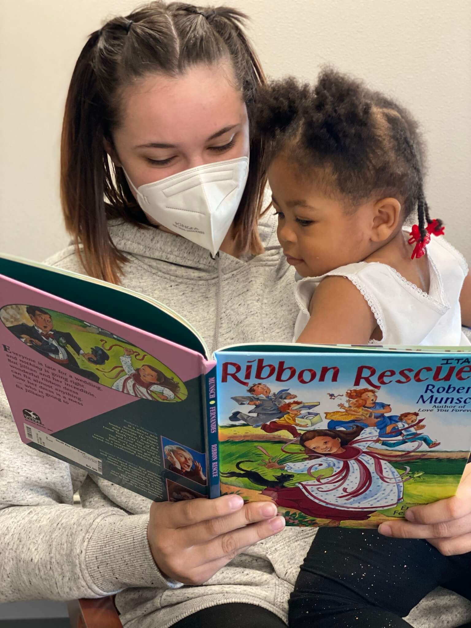 child engaged in a book read by a childcare provider