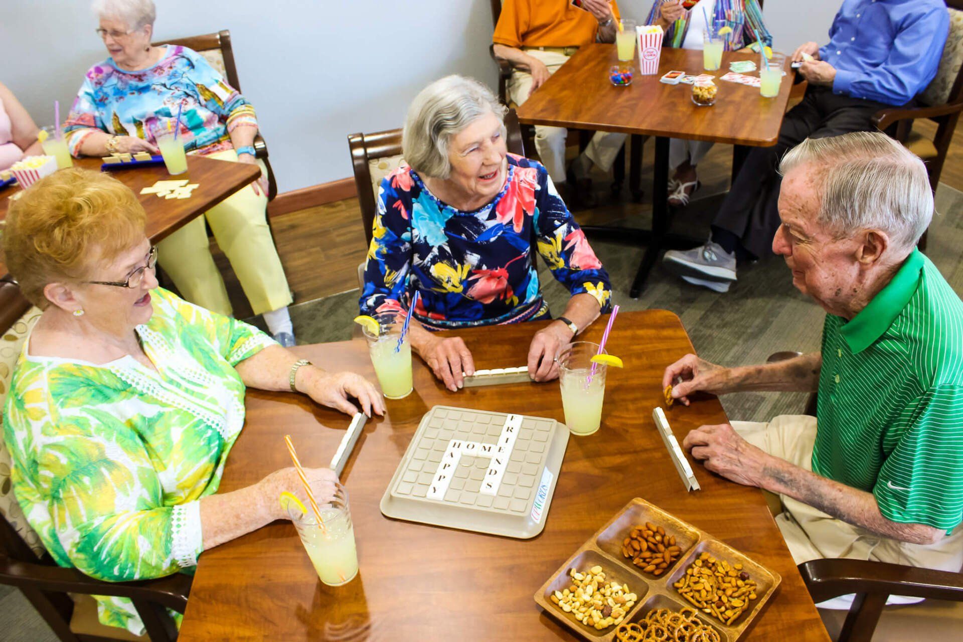 Active group of residents playing Scrabble and eating an assortment of snacks Active group of Friendship Village residents mingling and playing Scrabble in the Cove Lounge