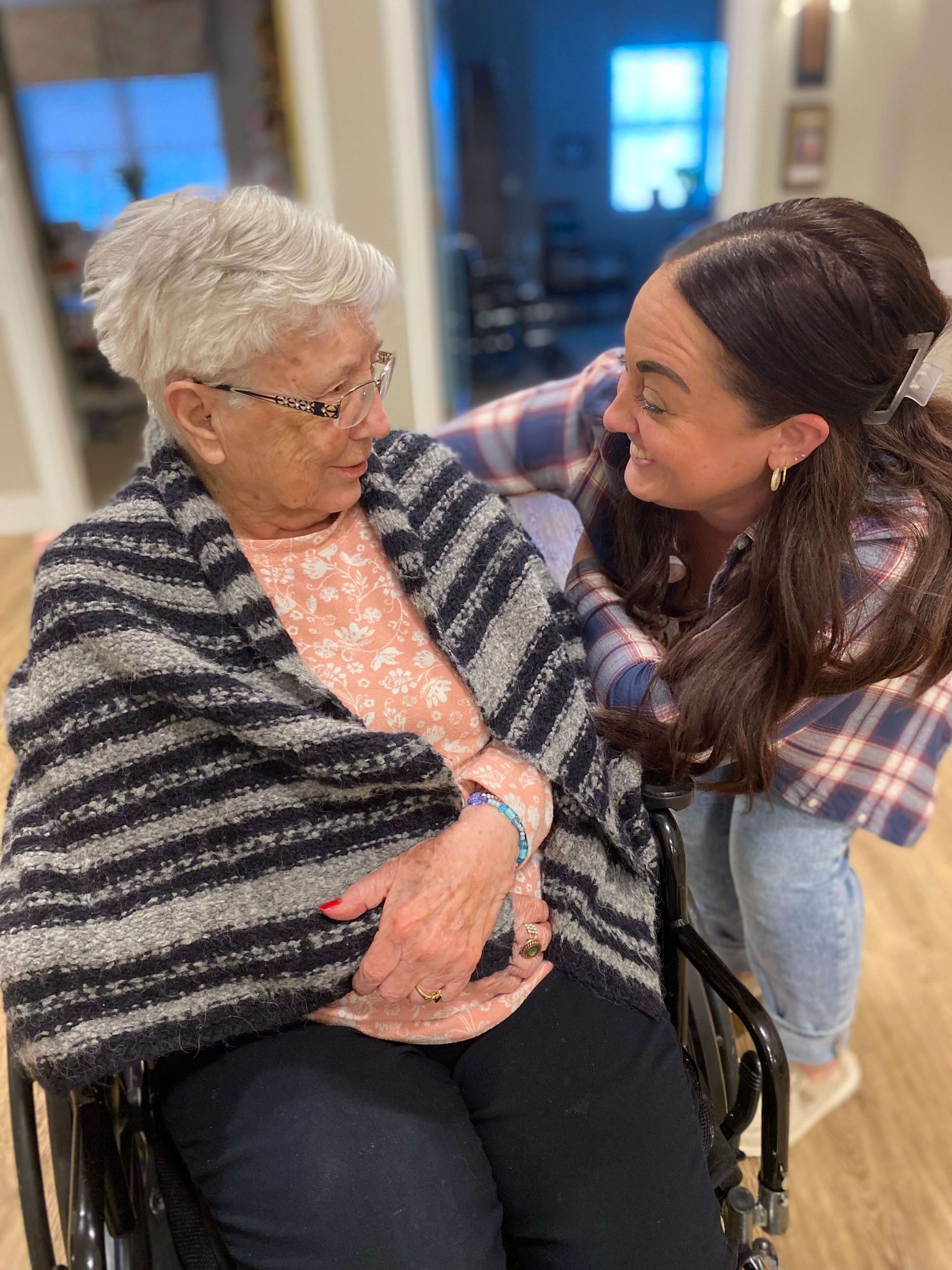healthcare worker pushing resident in wheelchair while talking to them