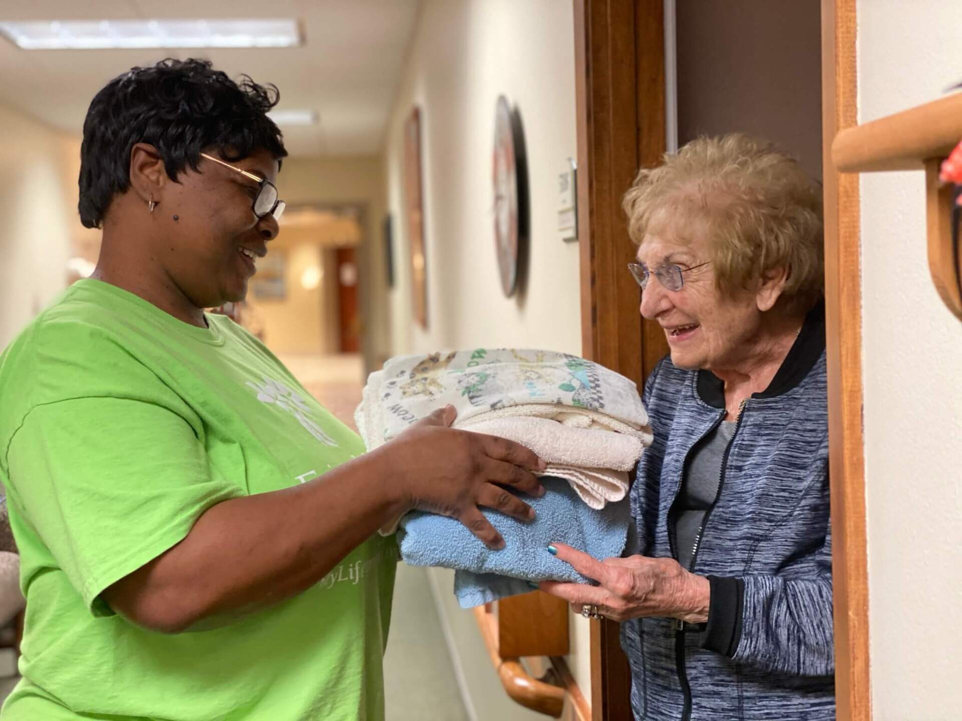 Housekeeper delivering clean towels to an independent living residents door step