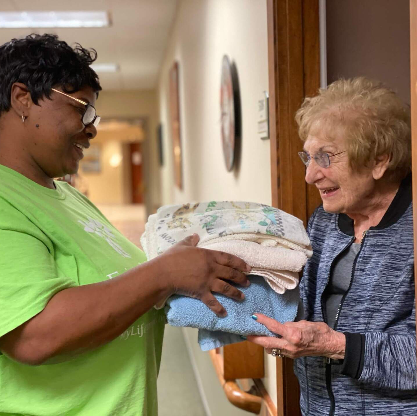 housekeeper handing towels to senior lady