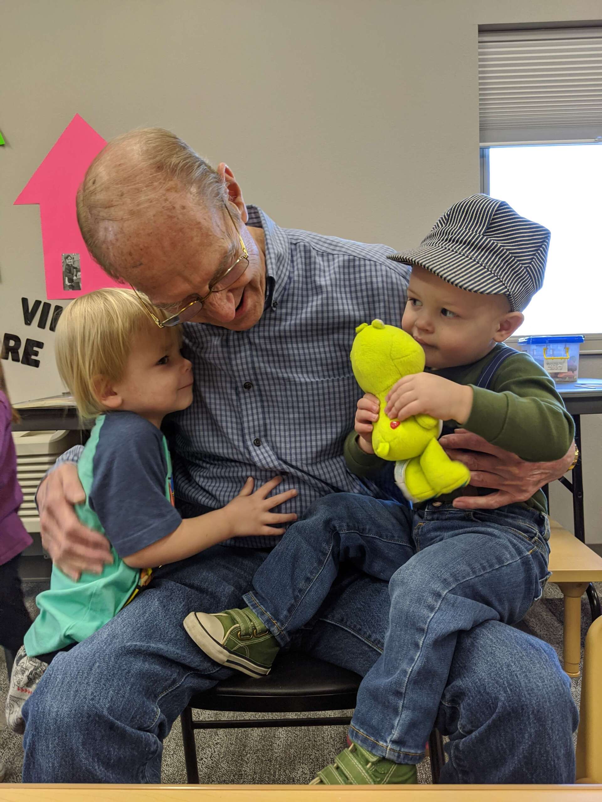 Senior man hugging and holding two boys at It Takes a Village Childcare Center