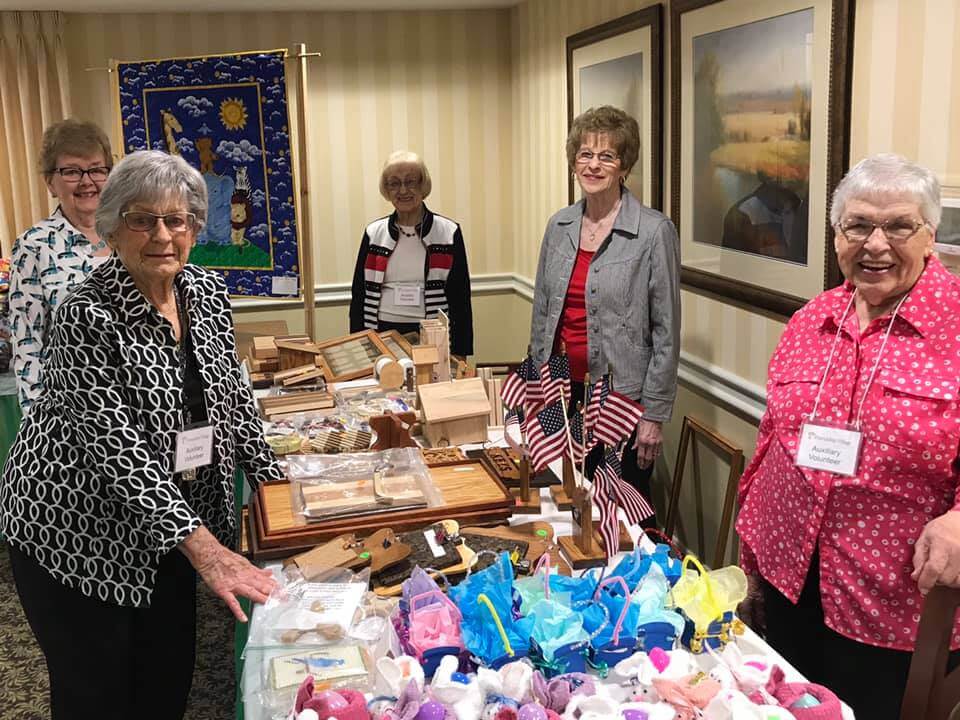 senior ladies displaying craft items at annual Auxiliary Brunch and Bazaar Independent living residents set up a craft shop to raise money for the Auxiliary